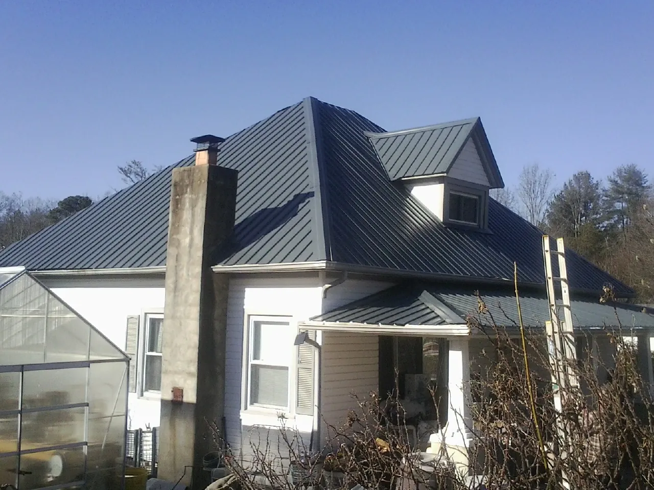 Dark blue standing seam metal roof on a white farmhouse with dormer — Slate & Tile Roof Repair by Roofing Brothers in New Alexandria