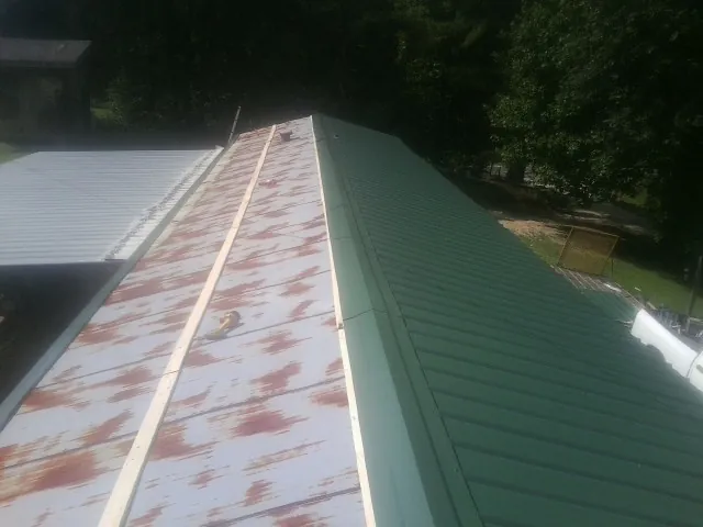 Old rusted panels beside newly installed green metal roofing — Wind Damage Roof Repair by Roofing Brothers in New Alexandria