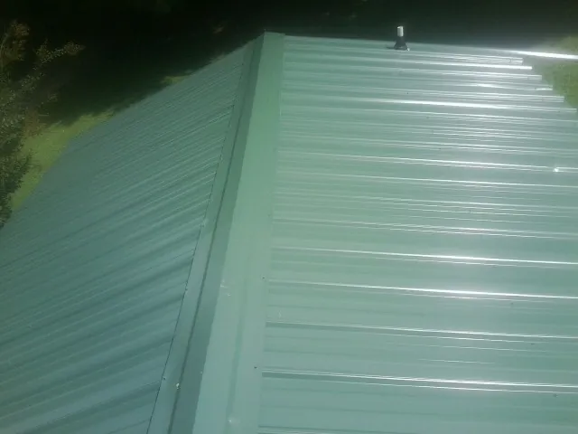 New green metal panels meeting at the ridge of a roof — Flat Roof Repair work by our crew in New Alexandria