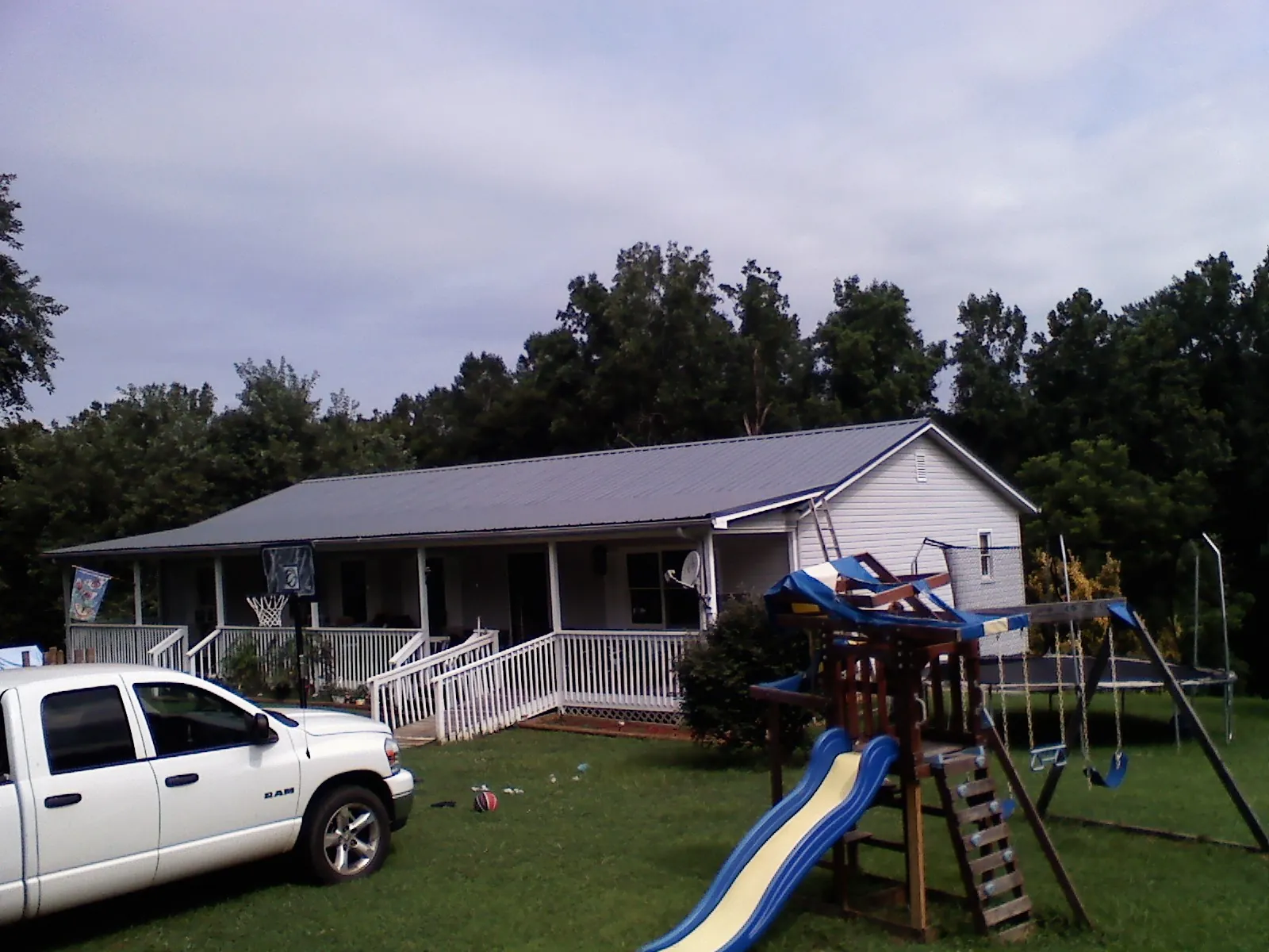 Dark metal roof on a country home with a full length front porch in New Alexandria