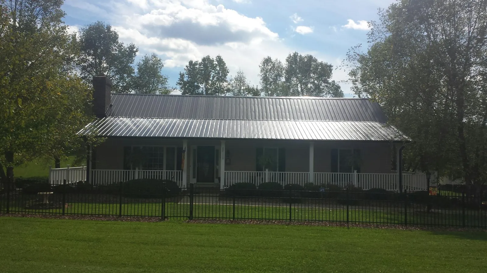 Gray metal roof on a brick ranch with a full width front porch — Gutter Guard Installation work by our crew in New Alexandria