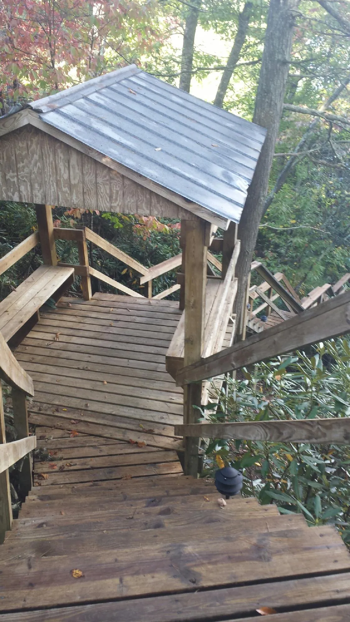 Metal roofed shelter over wooden steps on a wooded walkway — Skylight Repair & Installation work by our crew in New Alexandria