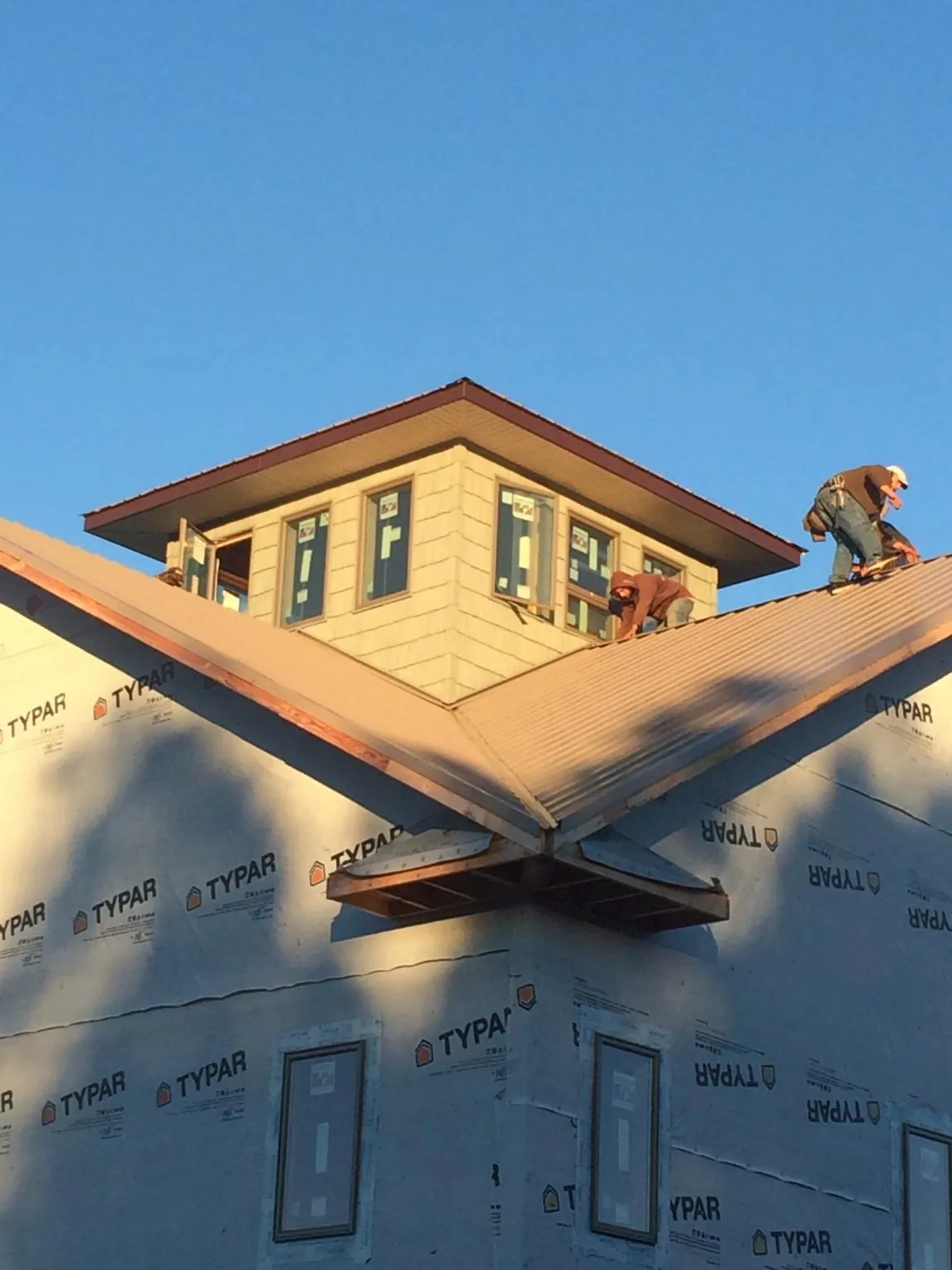 Roofers working around a rooftop cupola on a new metal roof at sunset — Roof Waterproofing in New Alexandria by Roofing Brothers